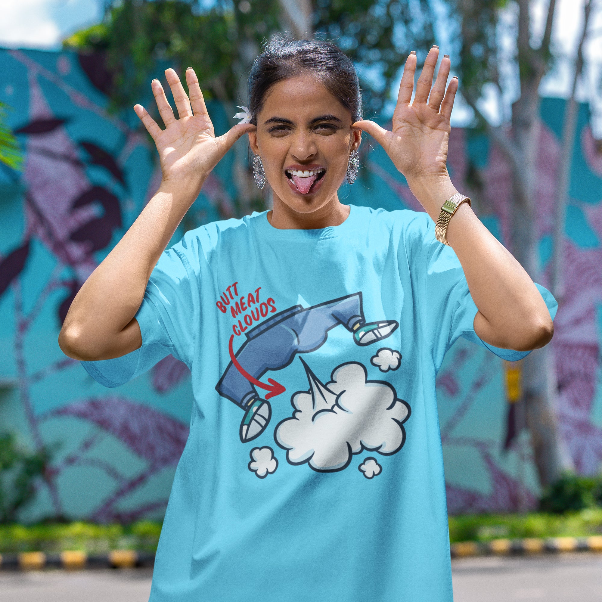 A woman wearing a blue t-shirt with a graphic design and making a playful gesture with her hands.