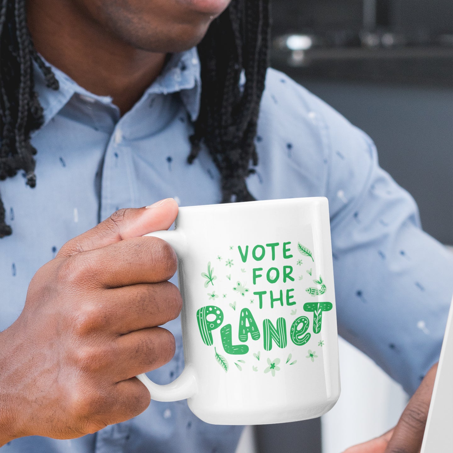 a man holding a coffee mug with the words vote for the planet printed on it