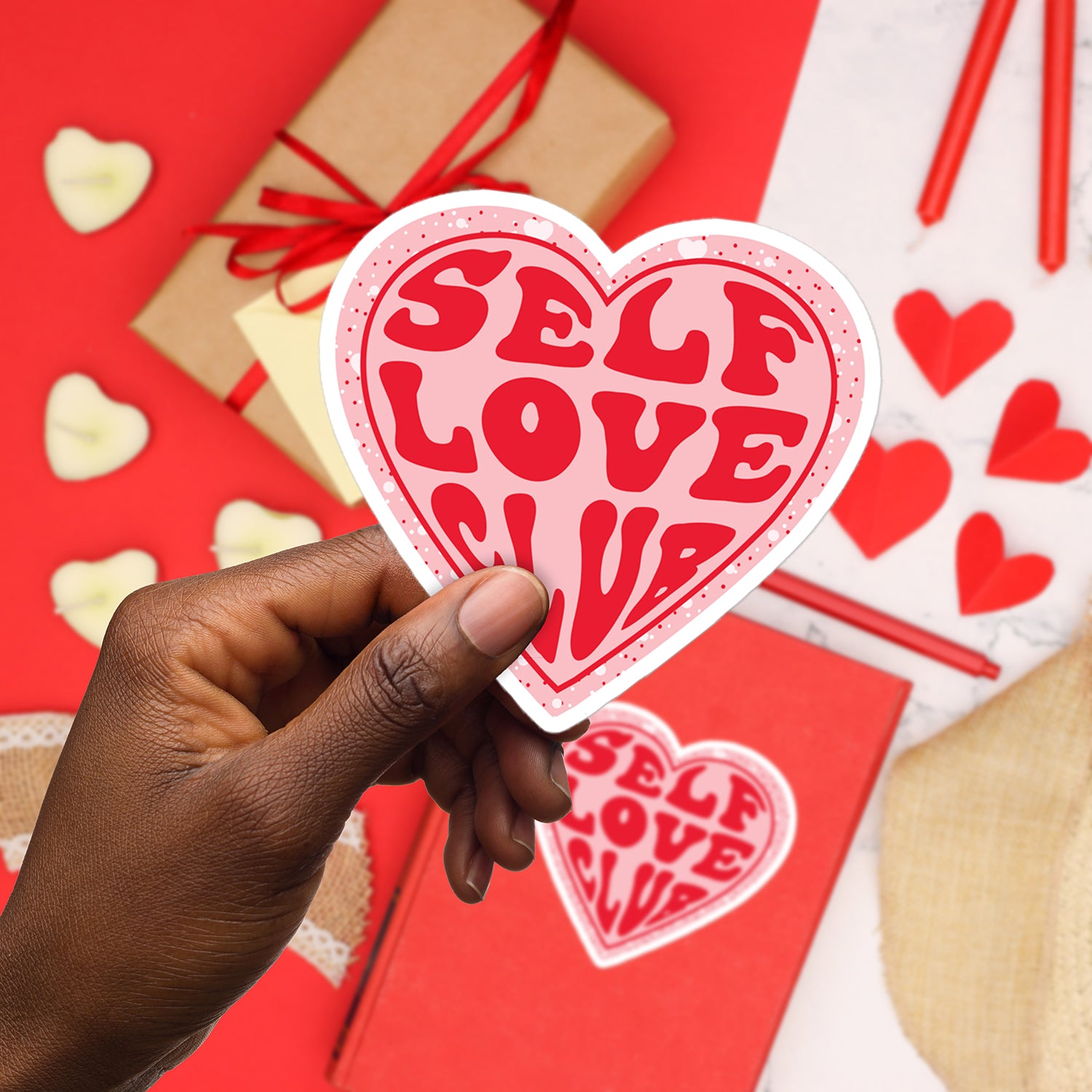 a hand holding up a heart shaped sticker