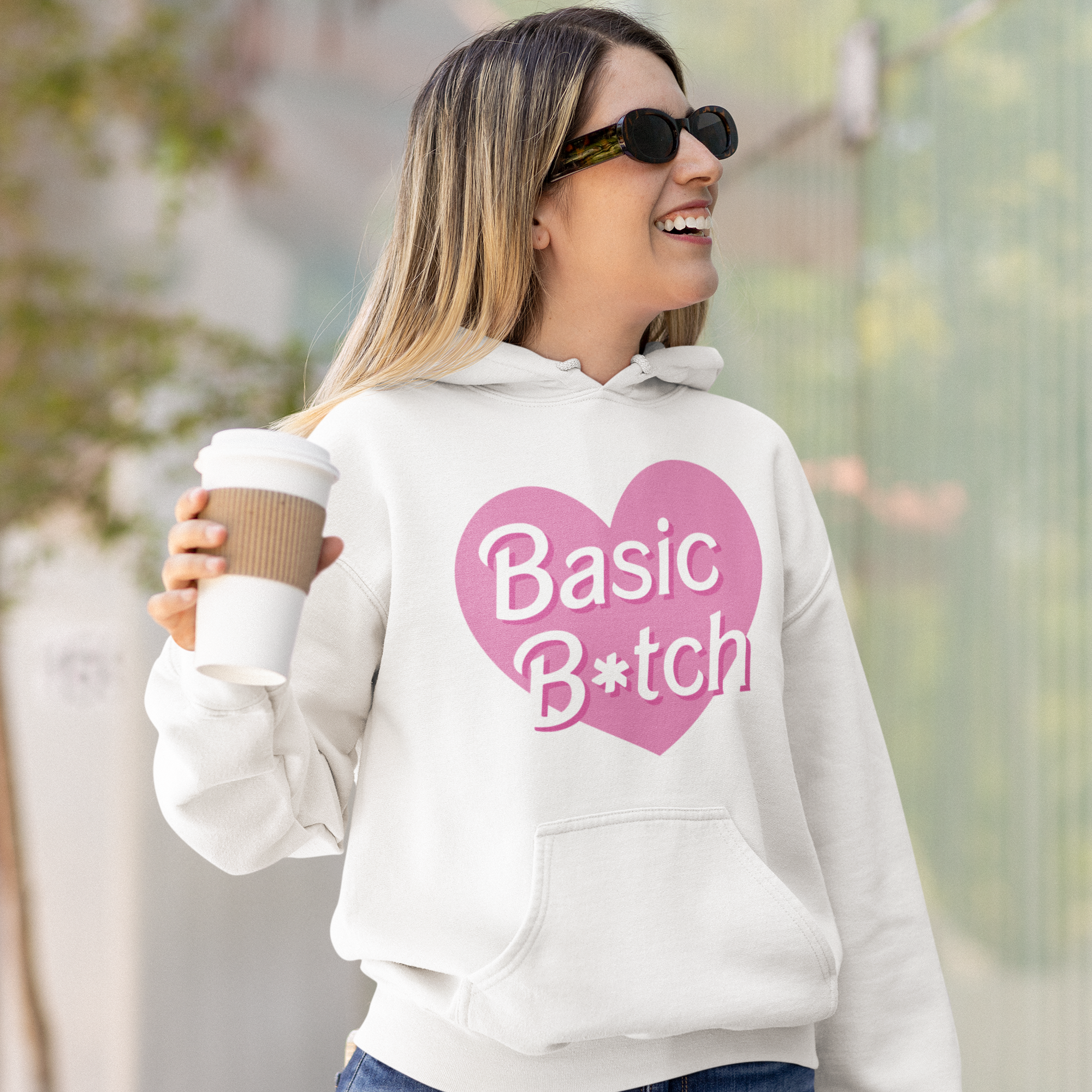 a woman holding a coffee cup and wearing a white basic bitch hoodie