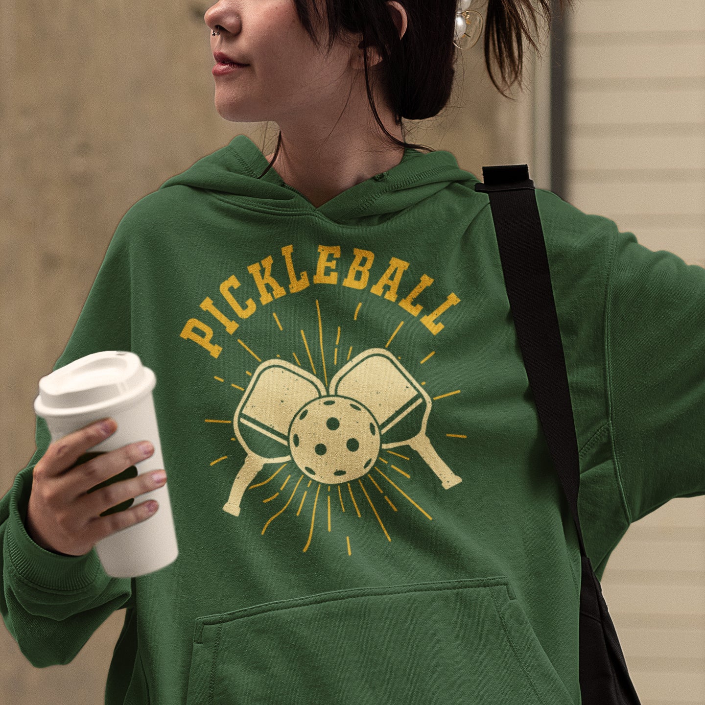 a woman in a green sweatshirt holding a cup of coffee