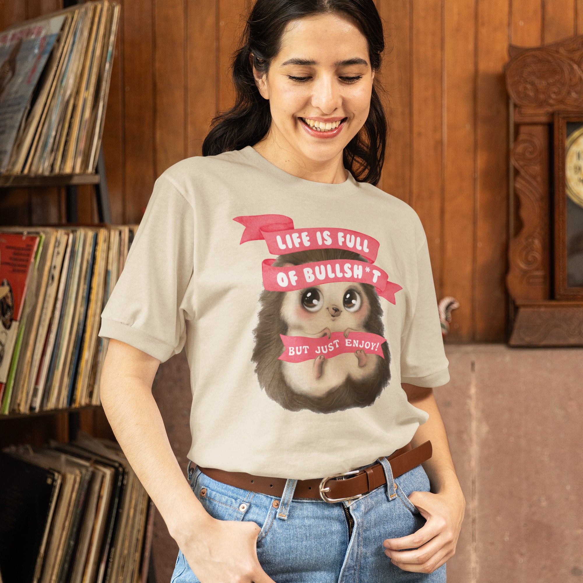 A woman wearing a t-shirt with a graphic of a hedgehog and text that says "Life is full of bulls*t but just enjoy".