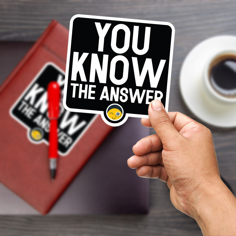 A hand holding a sticker with the text "YOU KNOW THE ANSWER" and a yellow smiley face sticker.
