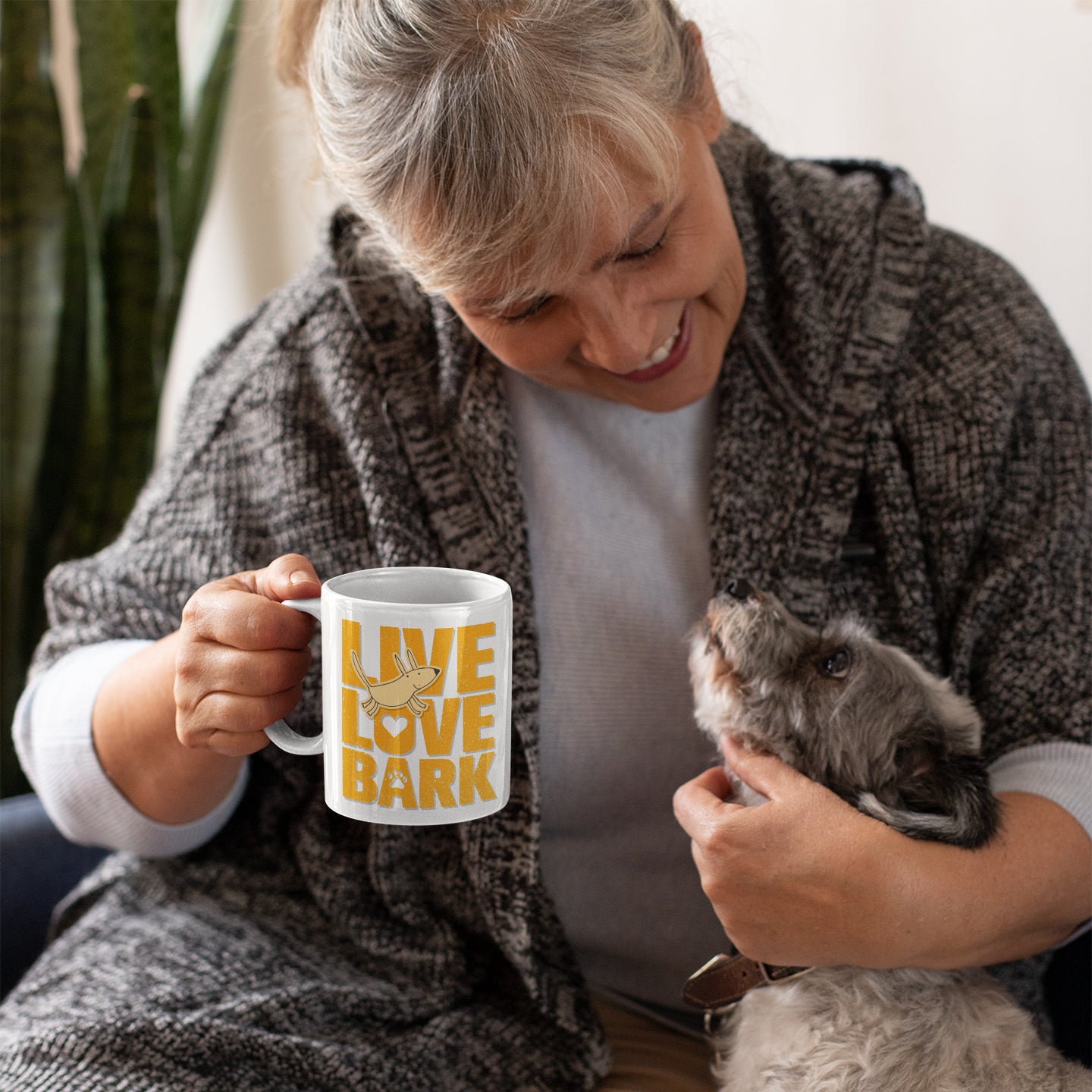 a woman holding a cat and a coffee mug