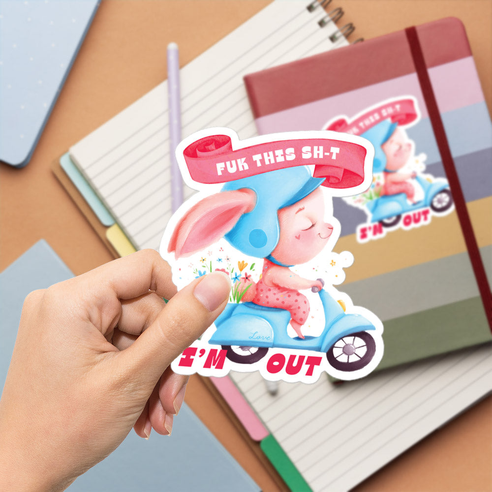 A hand is holding a sticker with a cartoon image of a pig riding a motorcycle, with the text "FUCK THIS SHIT" and "I'M OUT" printed on it.