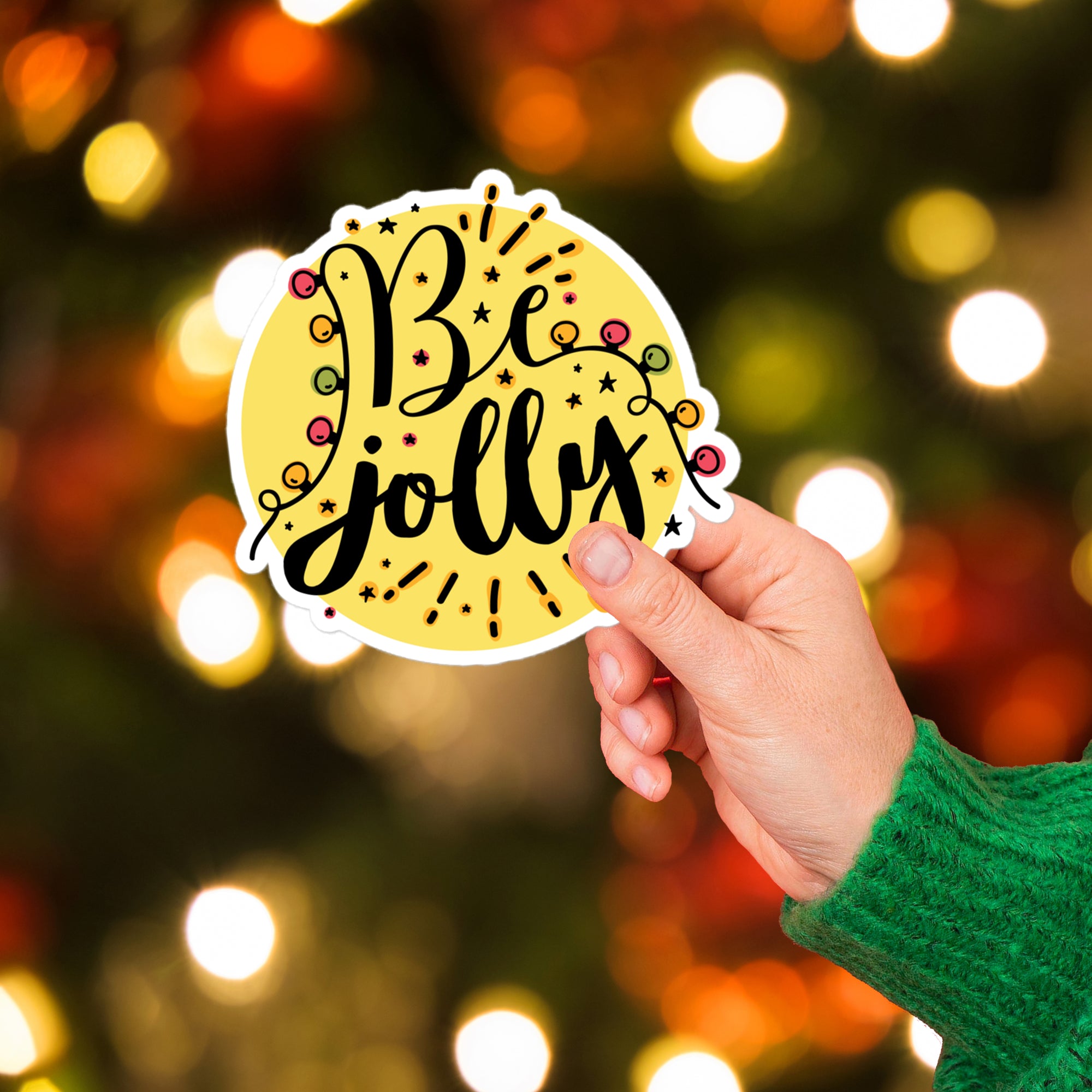 a hand holding a sticker that says be jolly