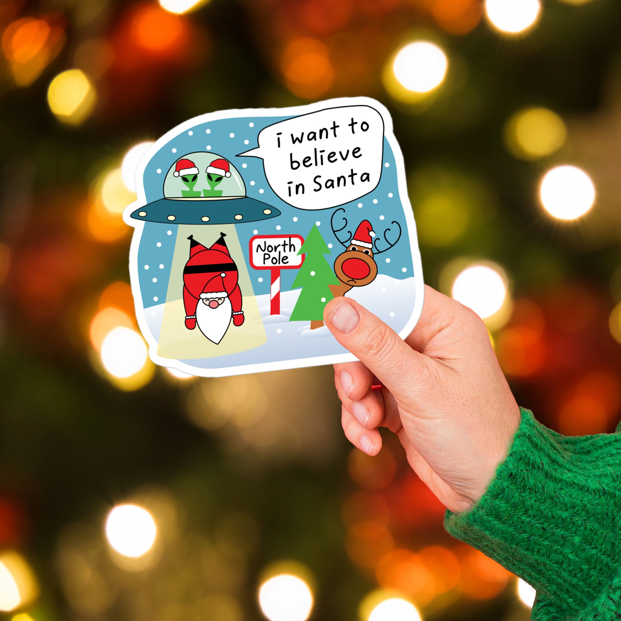 a hand holding a sticker with a santa clause saying i want to believe in