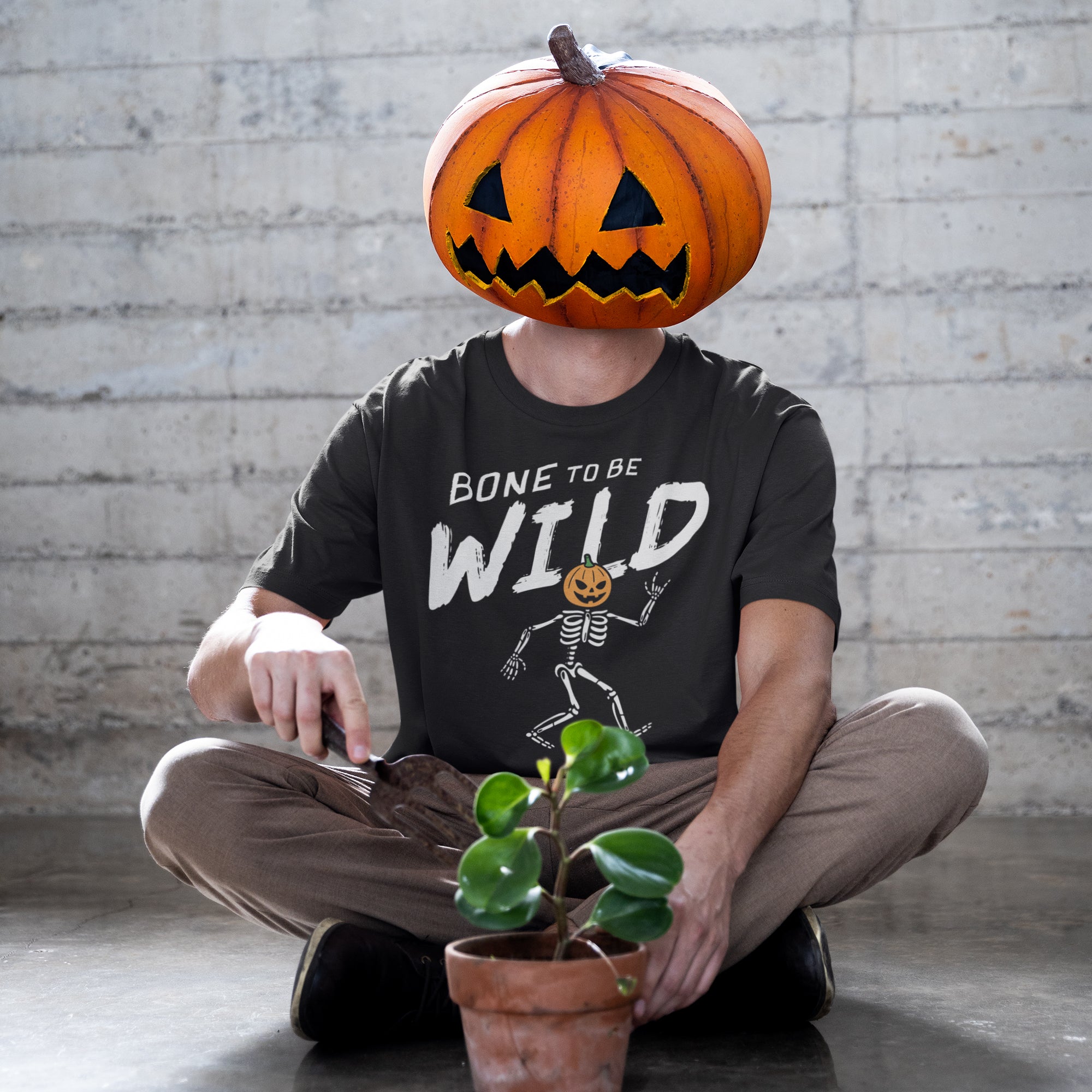 a man sitting on the ground with a pumpkin on his head