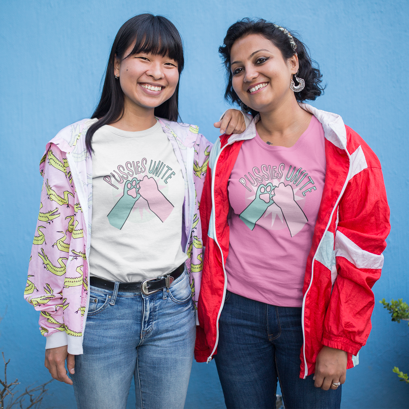 two women standing next to each other in front of a blue wall