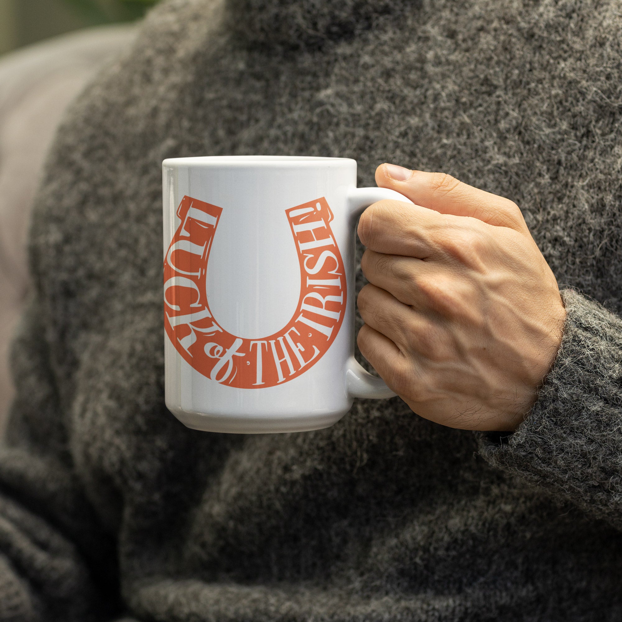 a person holding a coffee mug with a horseshoe on it