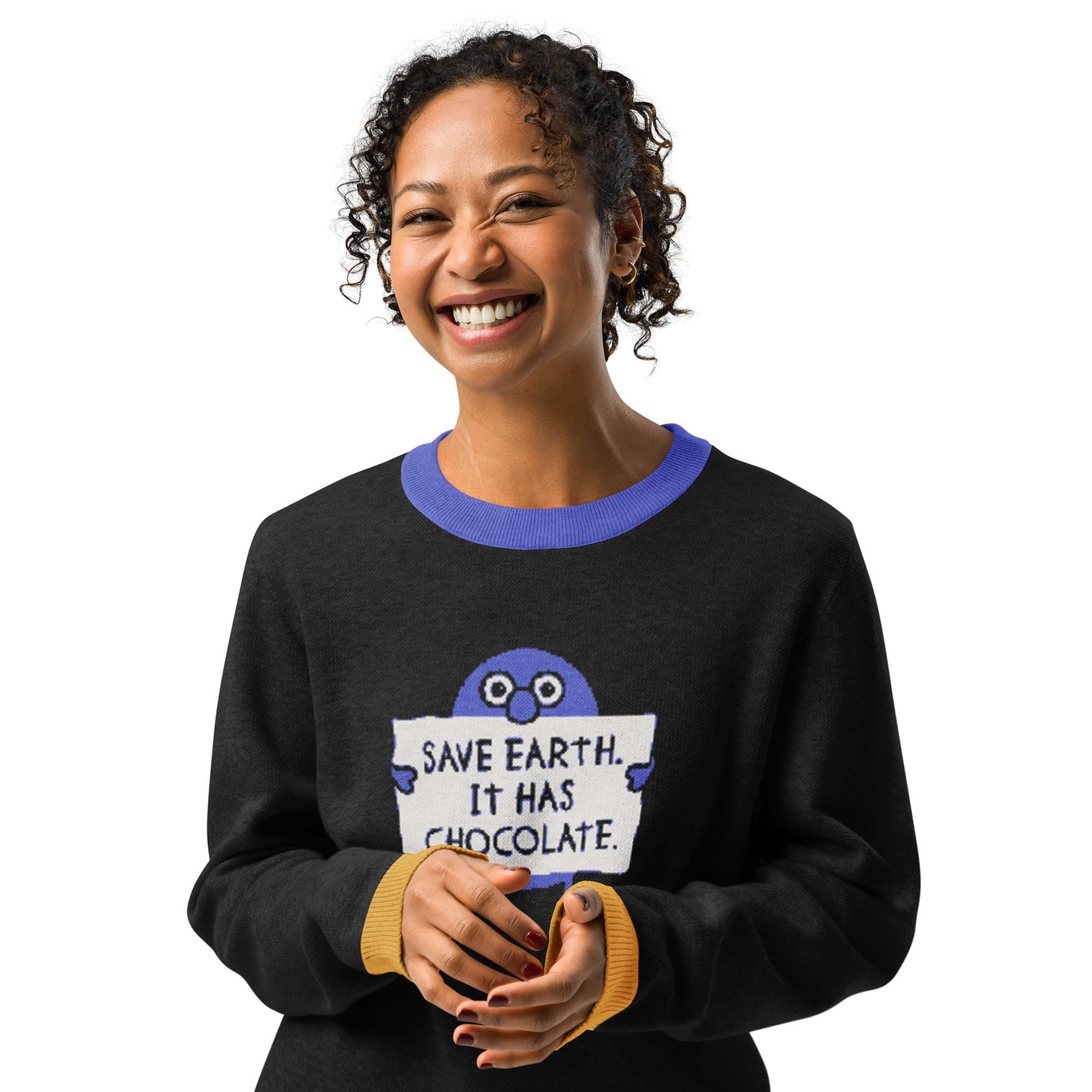A smiling woman wearing a black sweater with a graphic and text printed on it.