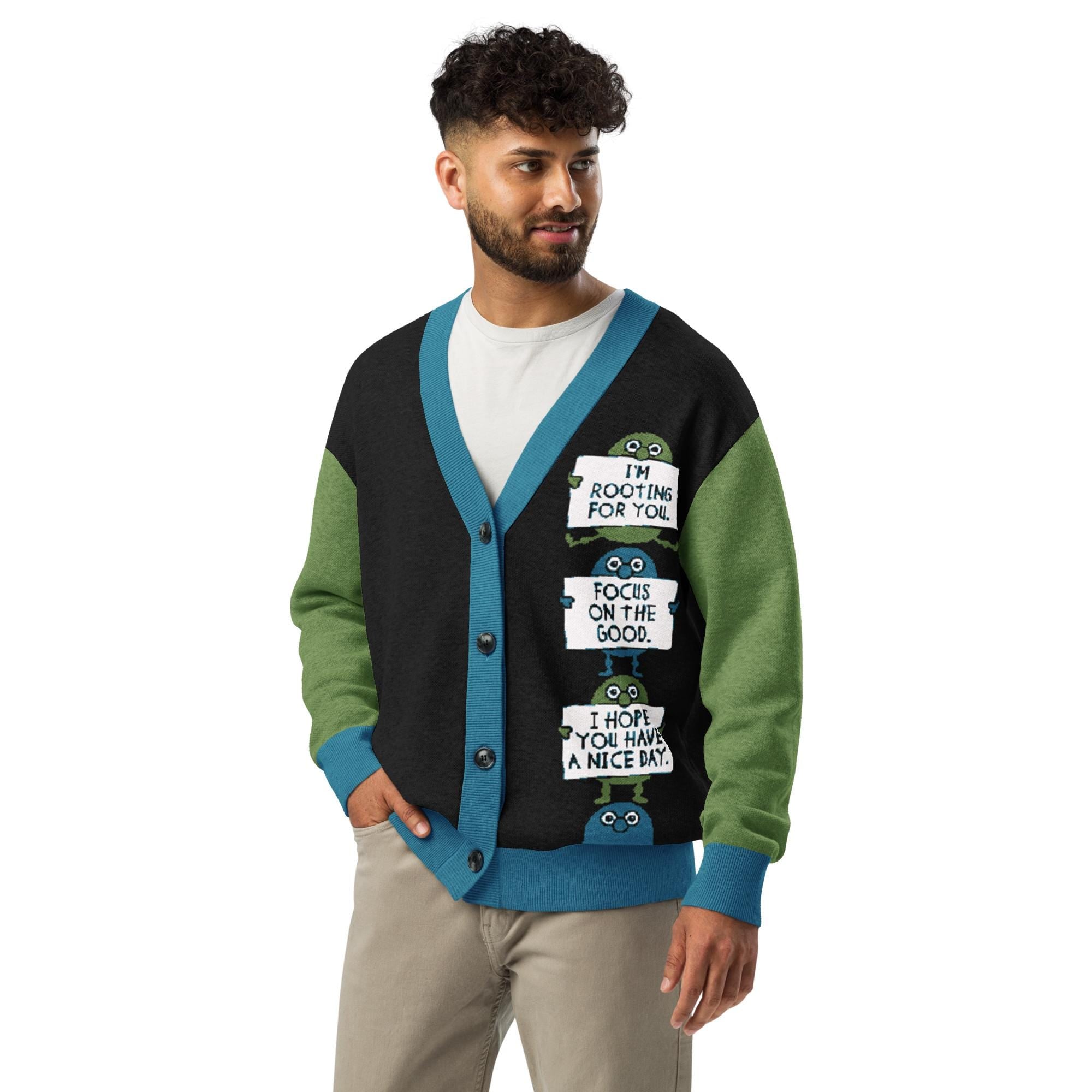 A man wearing a black and green cardigan with a humorous message printed on it.