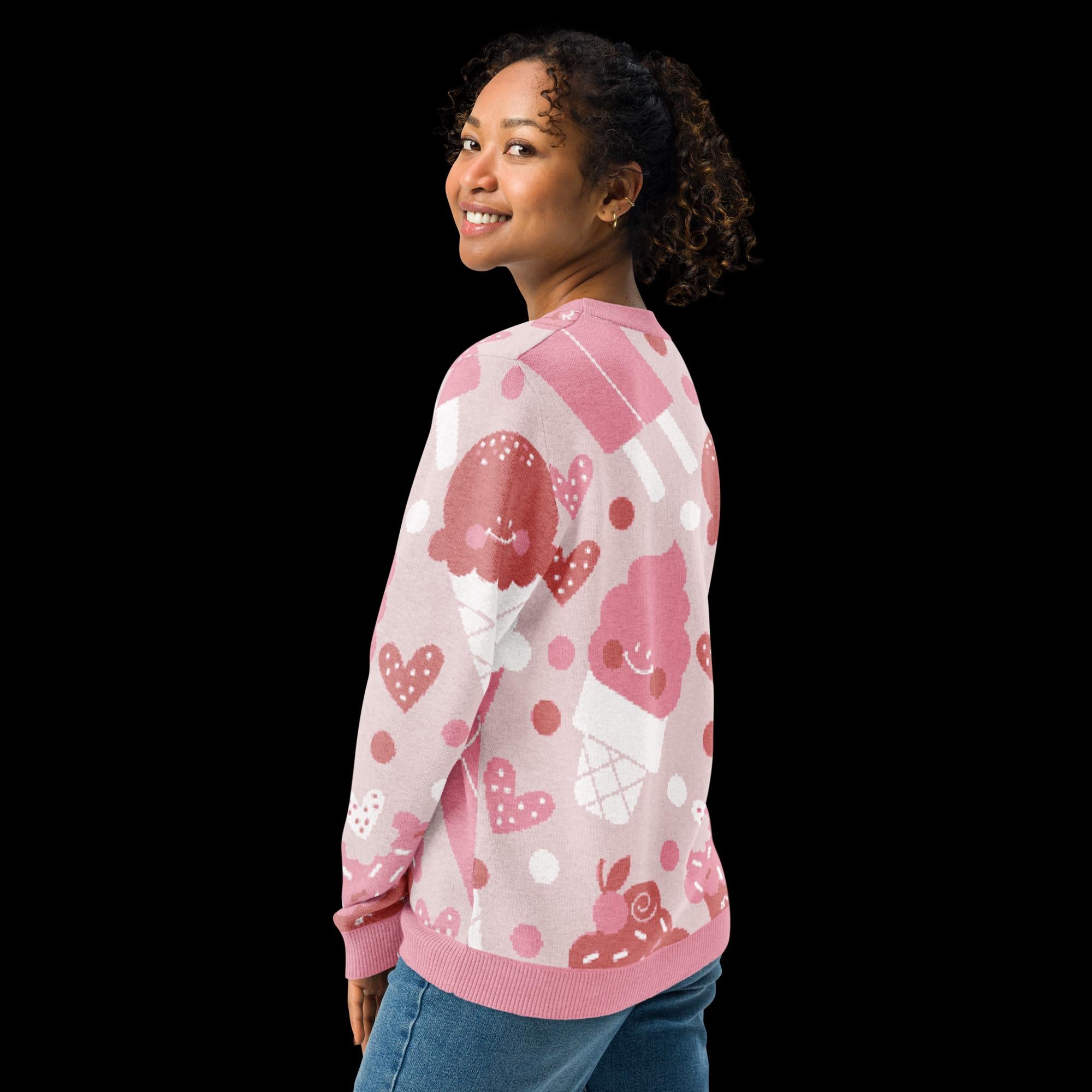 A smiling woman wearing a pink sweater with a playful pattern of ice cream cones and hearts.