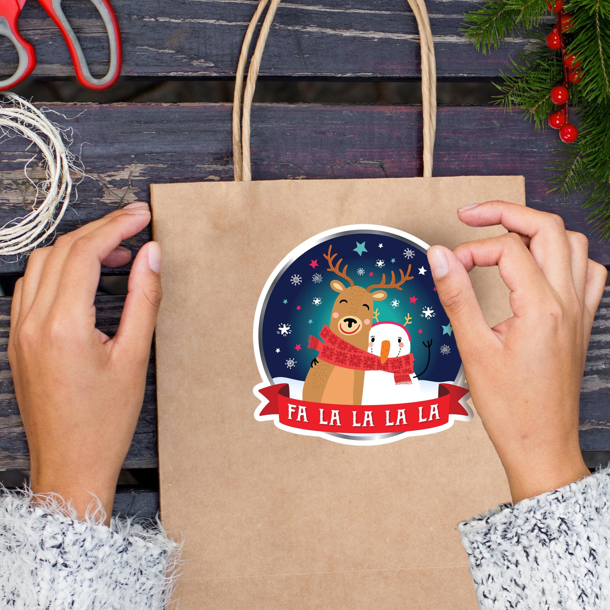 A person&#39;s hands holding a brown paper bag with a festive Christmas-themed sticker on it.