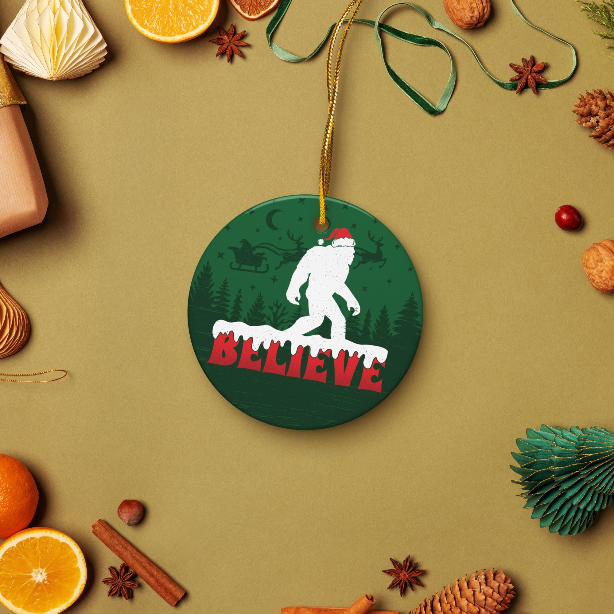 A Christmas ornament with a picture of a Sasquatch wearing a Santa hat, surrounded by various holiday decorations such as pine cones, oranges, and star anise.