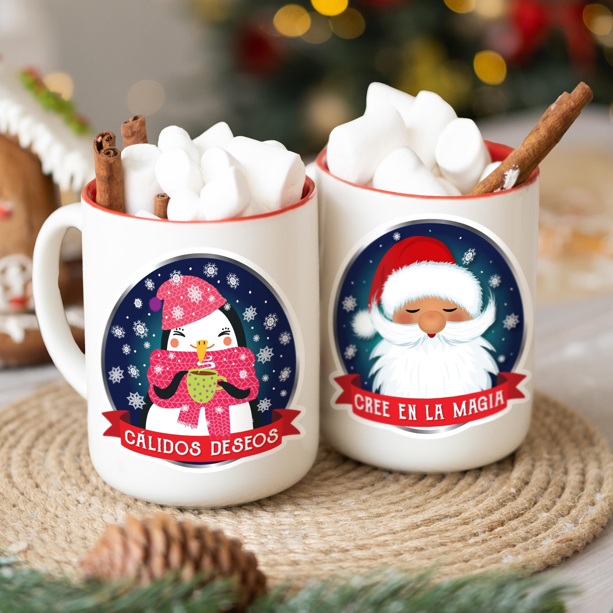 Two mugs with Christmas-themed designs, featuring Santa Claus and a penguin, are placed on a table with a pine cone and other holiday decorations.