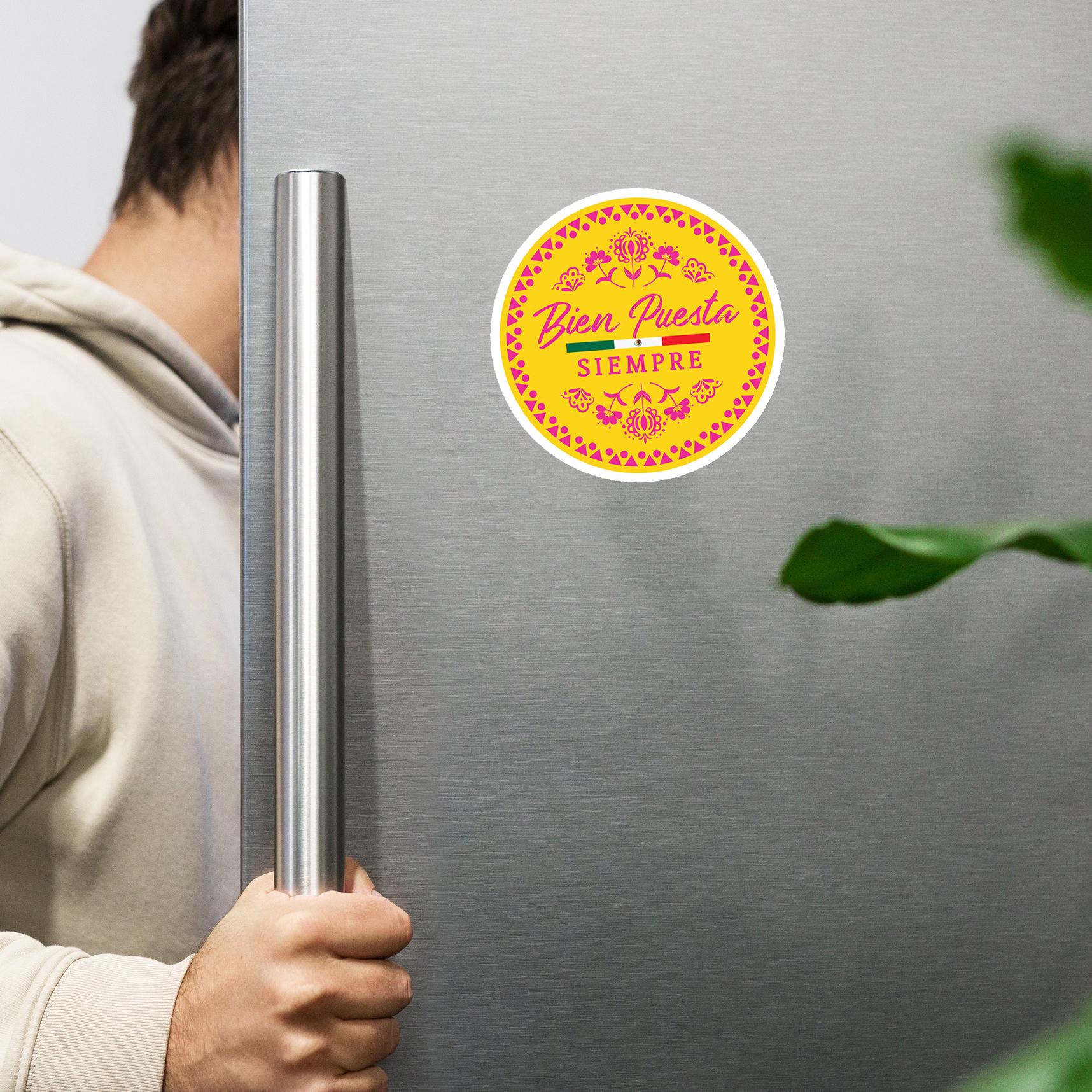 A person is holding the handle of a refrigerator with a sticker on it.