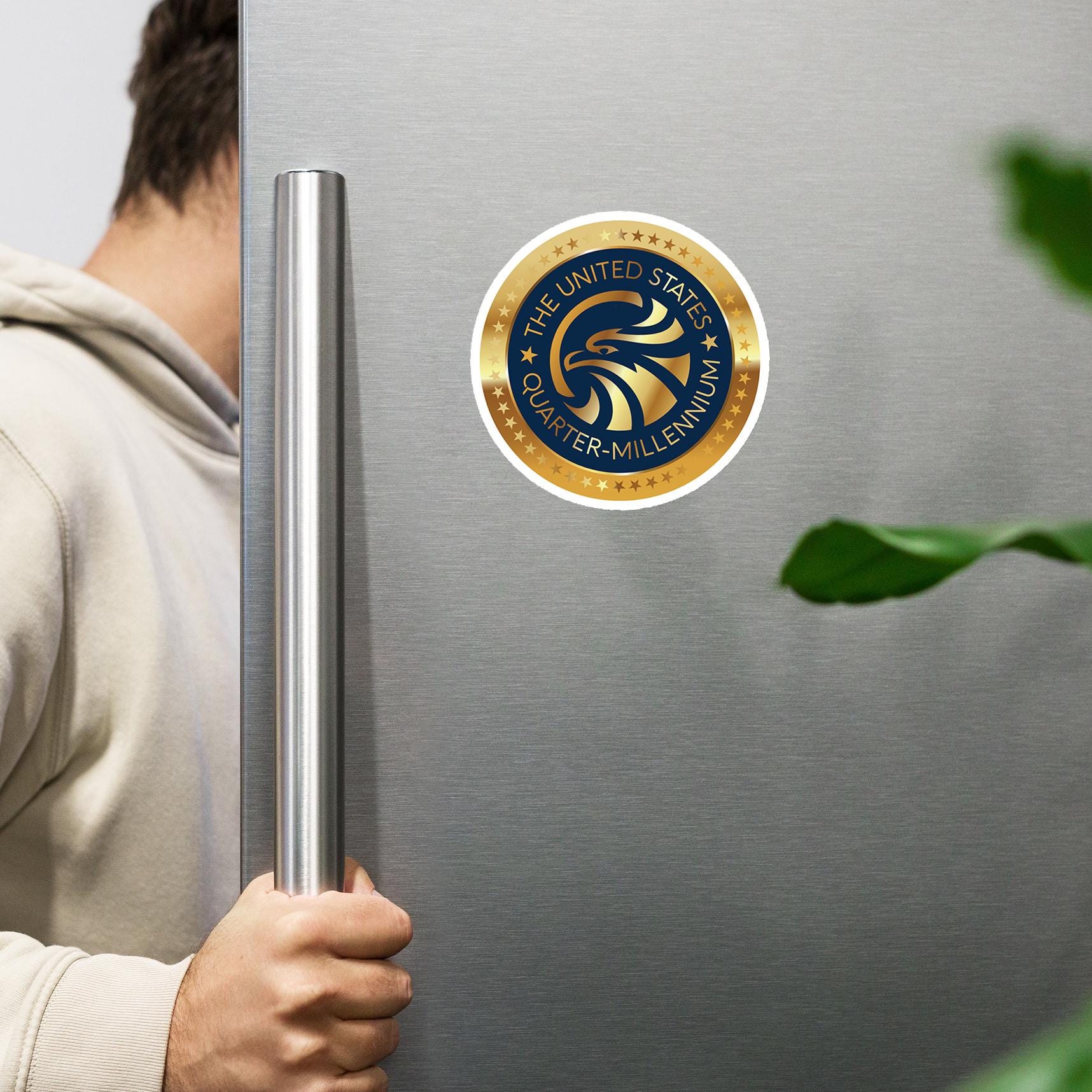 A person is holding a silver handle on a refrigerator door, with a United States quarter-millionth sticker visible on the door.