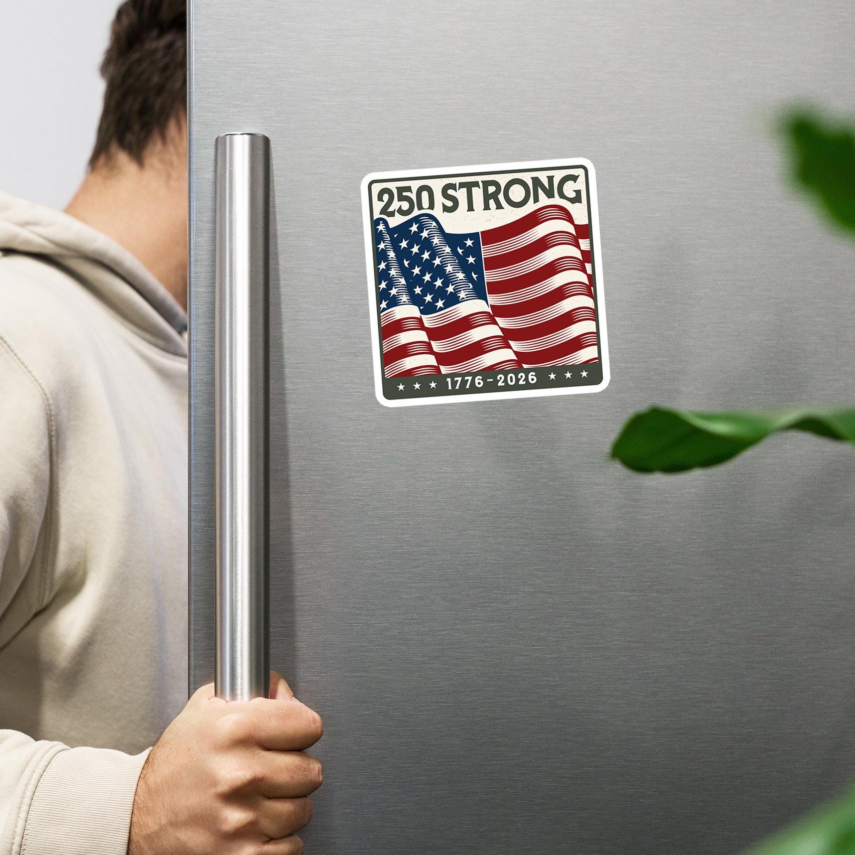 A person is holding a stainless steel refrigerator with a patriotic American flag sticker on it.
