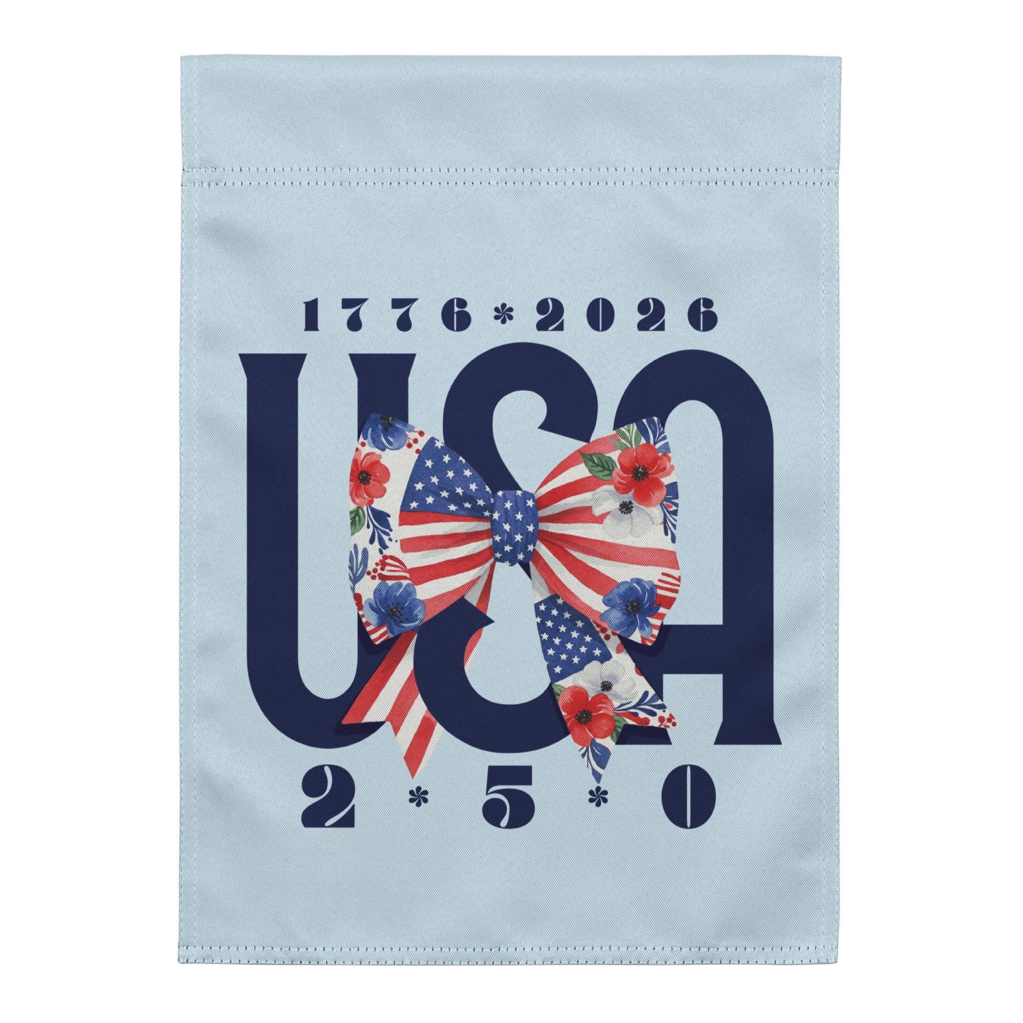 A flag with the text "1776-2026" and "USA" in large letters, along with a bow made up of the letters "USA" and flowers. The flag has a light blue background.
