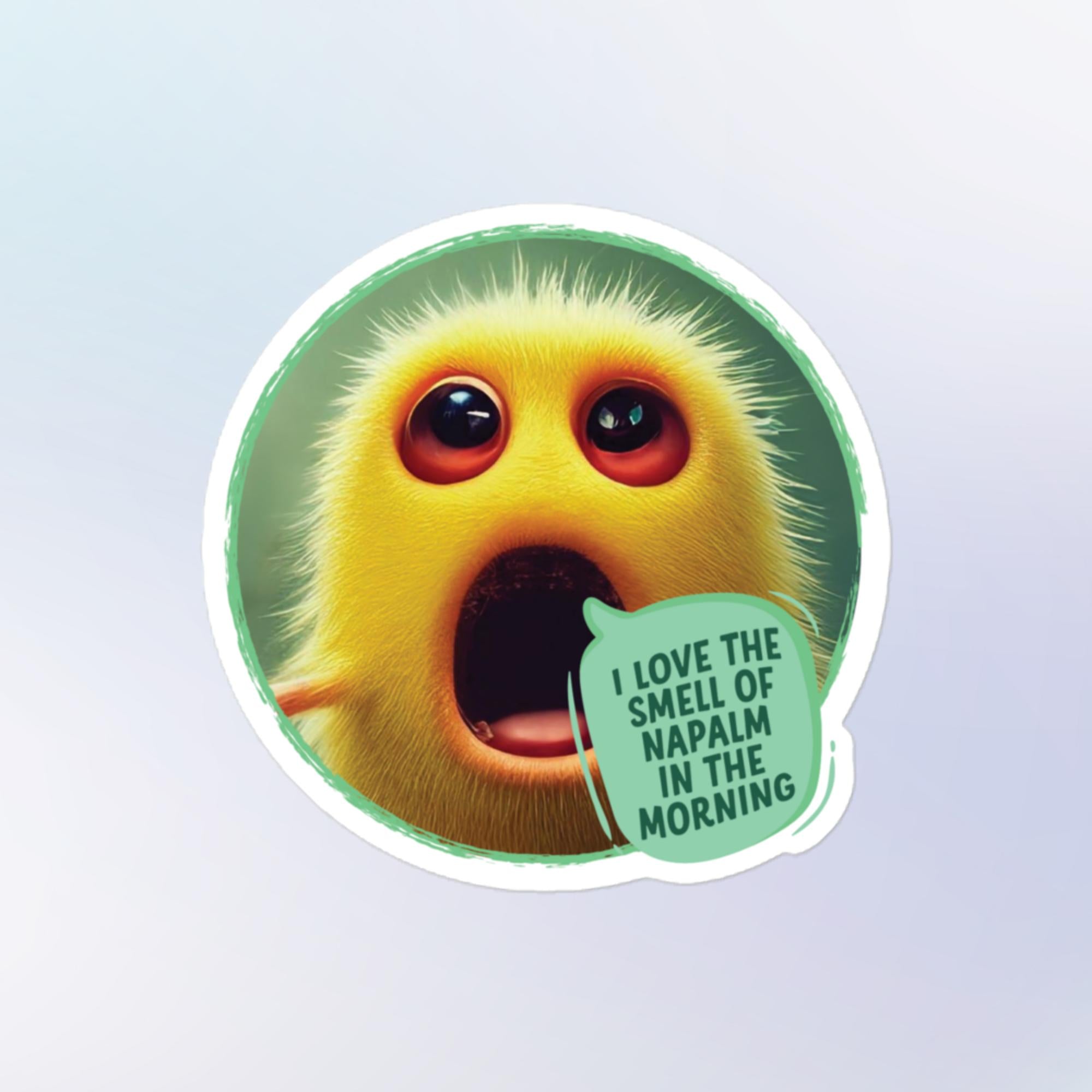 Sticker shape: Round. Design: A small bright yellow fuzz ball creature with big red eyes and its mouth agape stands yelling in front of a sage green background with a light green speech bubble that reads "I love the smell of napalm in the morning"